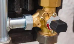 Valvola di sfogo caldaia in ottone, con manopola nera e indicatore di pressione. Si trova collegata a un tubo metallico.