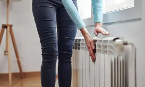 Mani che toccano un termosifone freddo, preoccupazione perché i termosifoni non si scaldano e la casa è gelida.