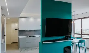 Un moderno cartongesso open space divide cucina e zona living con TV. Luce soffusa e colori vivaci.