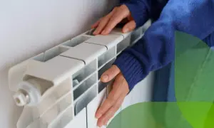Mani che toccano un termosifone bianco, suggerendo come svuotare un termosifone per la manutenzione.