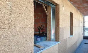 Blocchi di sughero, il miglior isolante termico naturale, rivestono le pareti di un edificio in costruzione, con aperture per finestre.