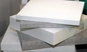 Pannelli bianchi e grigi di piastrelle isolanti termiche impilati, pronti per l'isolamento edilizio.