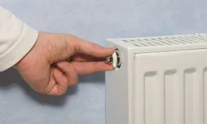 Mano che gira la valvola di uno spurgo termosifone. È il momento di capire quando spurgare i termosifoni per un riscaldamento efficiente.