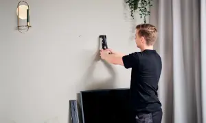 Uomo usa rivettatrice per rinforzare parete cartongesso, preparando il muro per un nuovo mobile.