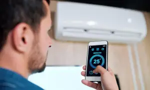 Uomo controlla condizionatore Mitsubishi con smartphone, mostrando come collegare condizionatore Mitsubishi wifi per gestire la temperatura da remoto.