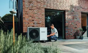 Installazione di una pompa di calore esterna: un uomo controlla l'unità posizionata vicino alla casa.