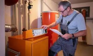 Tecnico controlla la caldaia, documentazione alla mano, per stimare il costo manutenzione caldaia.
