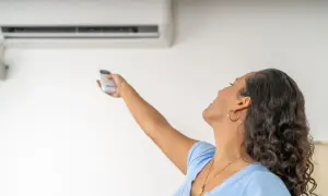 Donna con telecomando regola il condizionatore dal design elegante. La canalina è quasi invisibile, integrata perfettamente.
