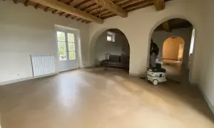 Interno con soffitto a travi, pareti in tinteggiatura a calce e un aspiratore professionale pronto per la pulizia.