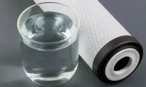 Un bicchiere d'acqua limpida accanto a un filtro. Per mantenere l'acqua pura, è importante sapere ogni quanto cambiare sali caldaia.