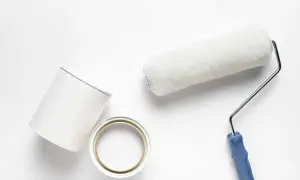 Pennello e barattolo di pittura bianca, pronti per dipingere. Valutare i pittura al quarzo svantaggi prima di iniziare.