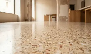 Pavimento lucido in cocciopesto veneziano, con riflessi di luce e mobili in legno sullo sfondo.