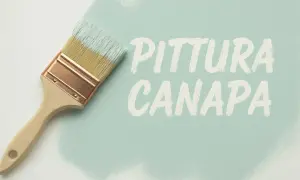 Pennello con calce a pennello che crea la scritta "PITTURA CANAPA" su una superficie chiara.