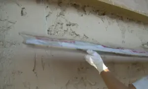 Applicazione di intonaco traspirante su una parete grezza con una spatola. La finitura garantisce la salute dell'edificio.