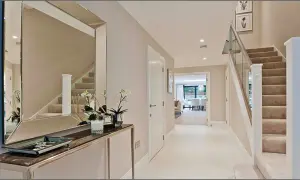 Ingresso moderno con specchio, consolle, scale e porta aperta su un'altra stanza.