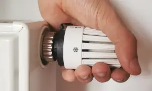 Regolare valvole termostatiche stanza per stanza: mano che gira la manopola del termosifone per impostare la temperatura desiderata.
