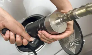 Mani che inseriscono un ugello per il rifornimento di gpl metano in un'auto.