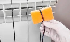 Guanto bianco e spugna arancione legata con cordino colorato, pronti per pulire i termosifoni.