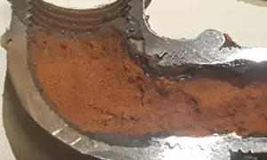 Sezione di tubo metallico con incrostazioni marroni che mostrano come evitare la formazione di calcare nelle tubazioni.