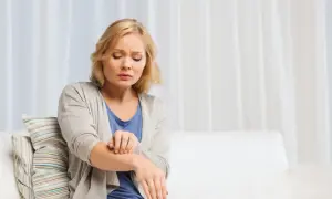 Donna si gratta il braccio, sofferente per l'aria secca che le irrita la pelle.