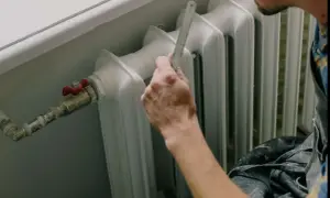 Mano che misura il detentore del termosifone con un righello.