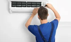 Tecnico con cacciavite apre un condizionatore per manutenzione. Il significato di "heat condizionatore" è la sua capacità di riscaldare.