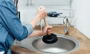 Persona usa uno sturalavandini per risolvere il problema di come sturare il lavandino della cucina.