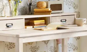 Scrivania chiara con cassetti, libri, tazza e radio vintage. Ideale per chi vuole imparare come verniciare un mobile da marrone a bianco.