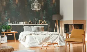 Camera da letto con un letto bianco, camino e una poltrona gialla, il tutto incorniciato da una suggestiva carta da parati effetto corten.