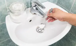 Mano versa bicarbonato nel lavandino per pulire le tubature.