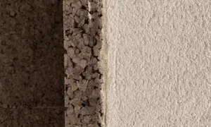 Dettaglio di un muro con strato di intonaco con sughero grezzo e finitura chiara e ruvida.