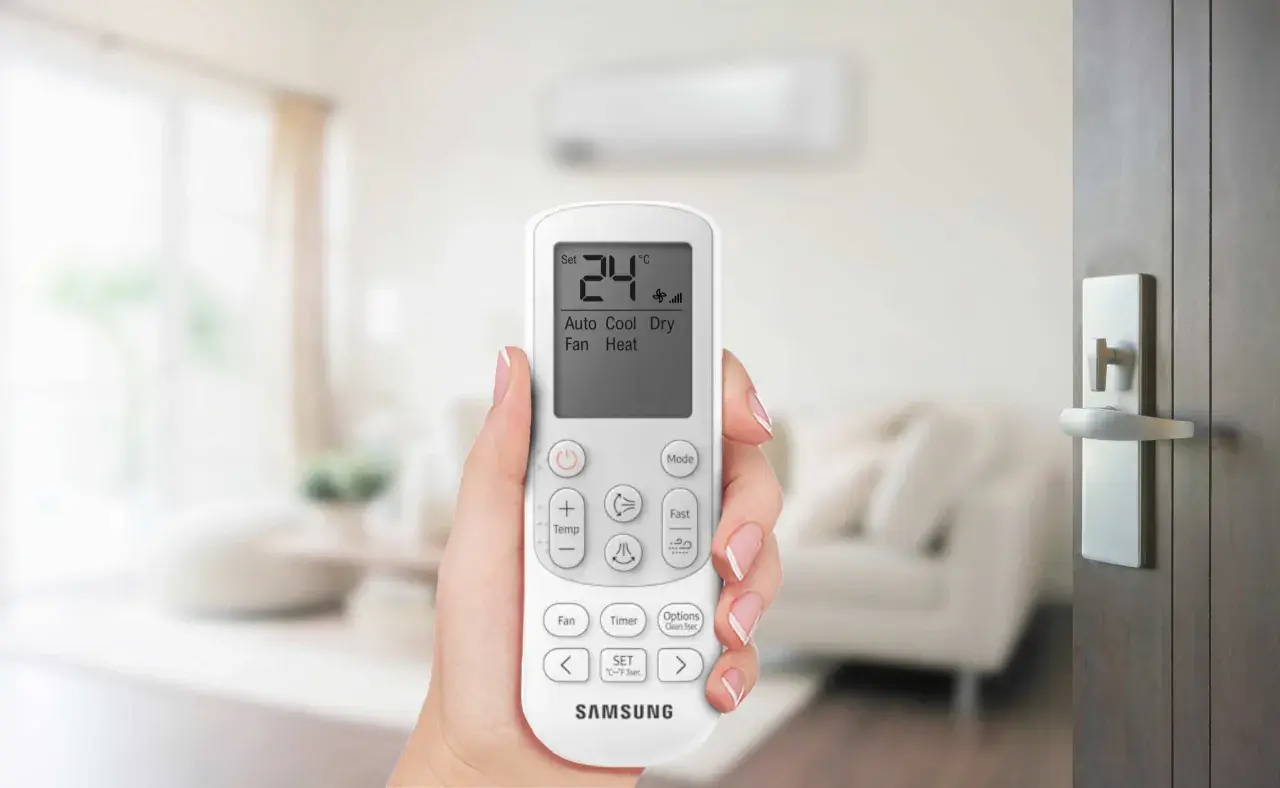 Mano che tiene il telecomando di un condizionatore Samsung. Il display mostra 24°C, Auto, Cool, Dry, Fan, Heat. Il significato di un condizionatore potente è il comfort.