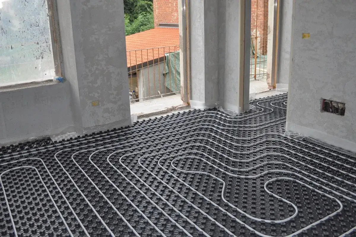 Installazione di un sistema di riscaldamento a pavimento in una casa in costruzione. Tubi bianchi su pannelli neri coprono l'intero pavimento.