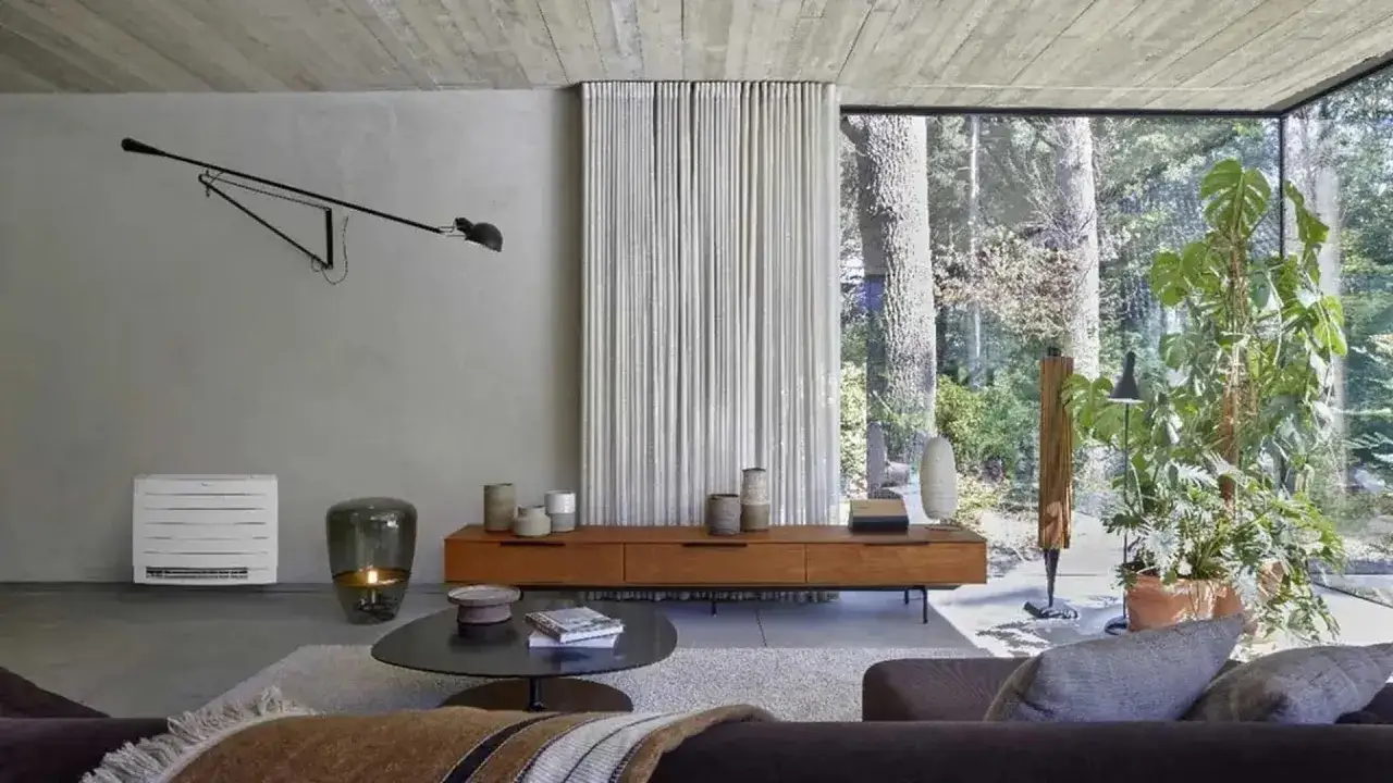 Un elegante soggiorno moderno con un'aria condizionata a pavimento discreta, un mobile in legno e una grande finestra che si affaccia su un giardino lussureggiante.