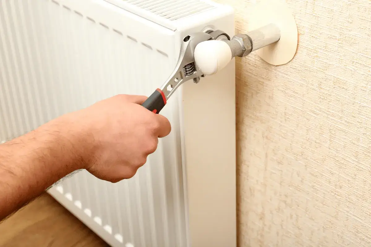 Mano con chiave inglese che agisce sulla valvola di un termosifone, un passo per imparare come svuotare un termosifone.