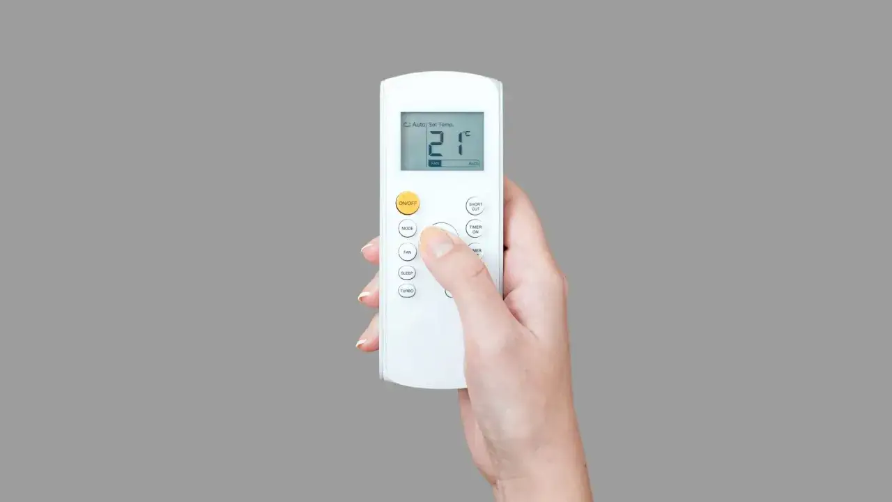 Mano che regola il telecomando di un potente condizionatore, impostando la temperatura a 21°C per un comfort ottimale.