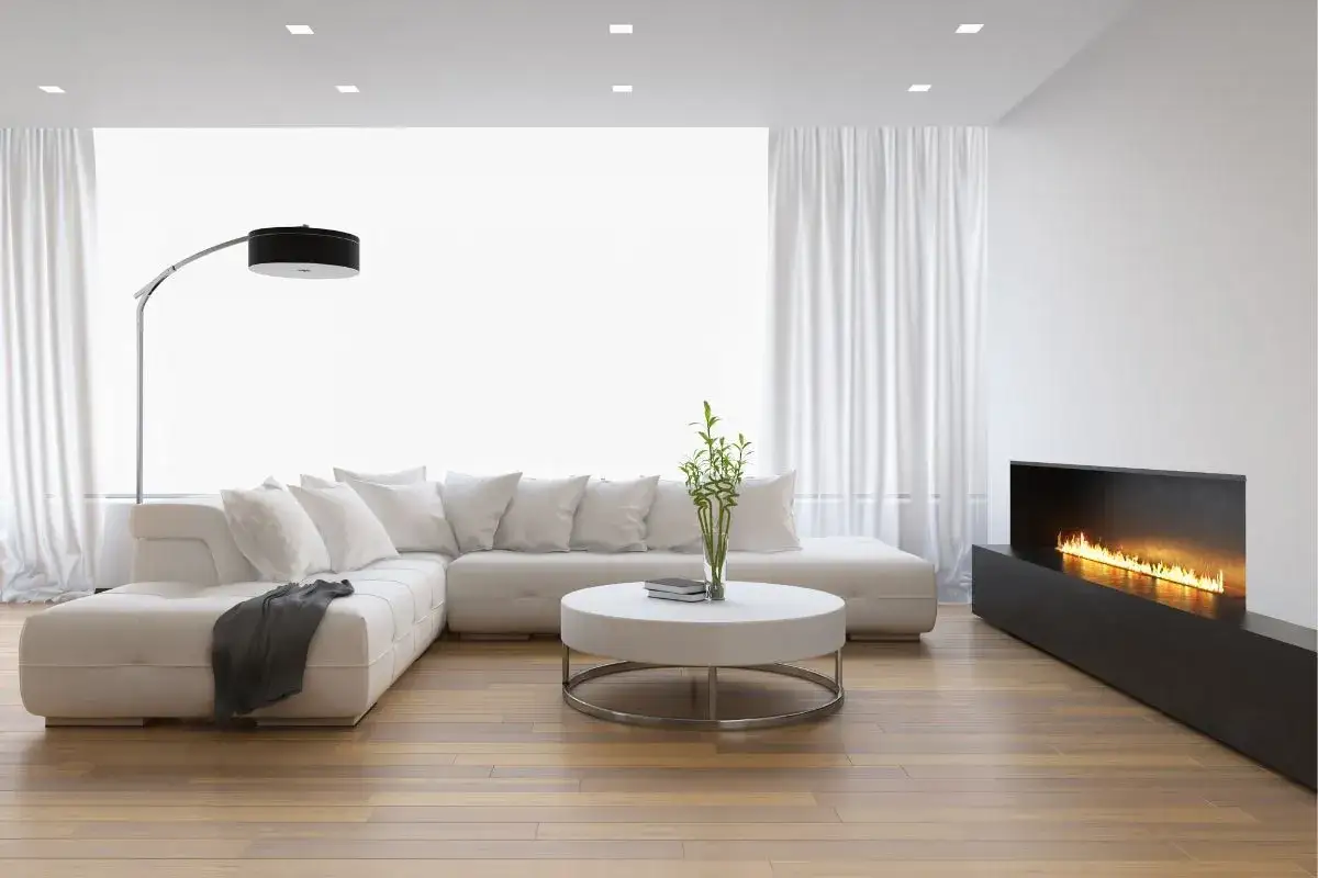 Soggiorno moderno con divano bianco, tavolino e camino a bioetanolo. Una stufa a bioetanolo conviene per un calore pulito e un design elegante.