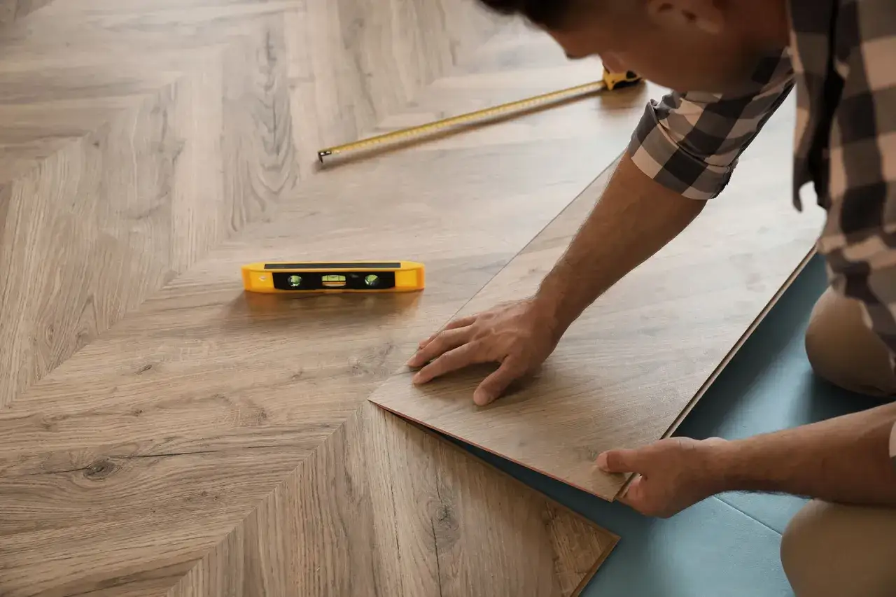 Installazione di piastrelle isolanti termiche in laminato effetto legno, con livella e metro a nastro a portata di mano.
