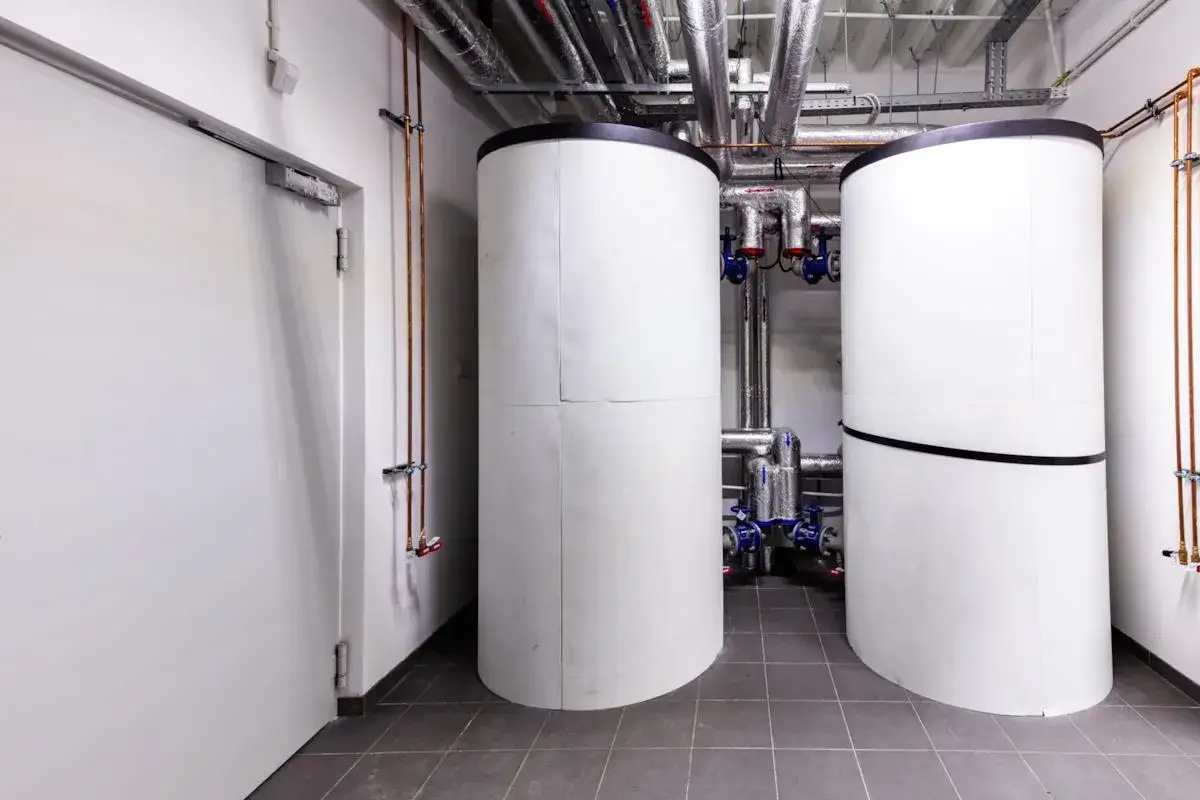 Due serbatoi bianchi isolati, parte di un sistema di puffer pompa di calore, sono collegati da tubature metalliche.