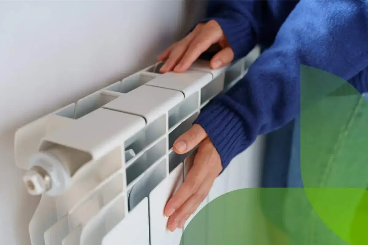 Mani che toccano un termosifone bianco, suggerendo come sfiatare i termosifoni per un riscaldamento efficiente.