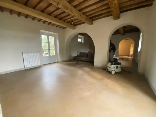 Interno con soffitto a travi, pareti in tinteggiatura a calce e un aspiratore professionale pronto per la pulizia.