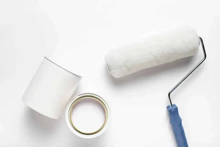 Pennello e barattolo di pittura bianca, pronti per dipingere. Valutare i pittura al quarzo svantaggi prima di iniziare.